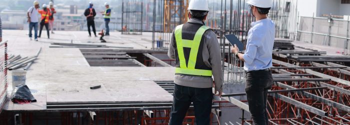 Two engineers work on the construction site. They are checking the progress of the work.